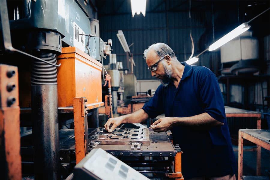 Man Working Machine Holding Rubber Parts Manufacturer in Warren MI